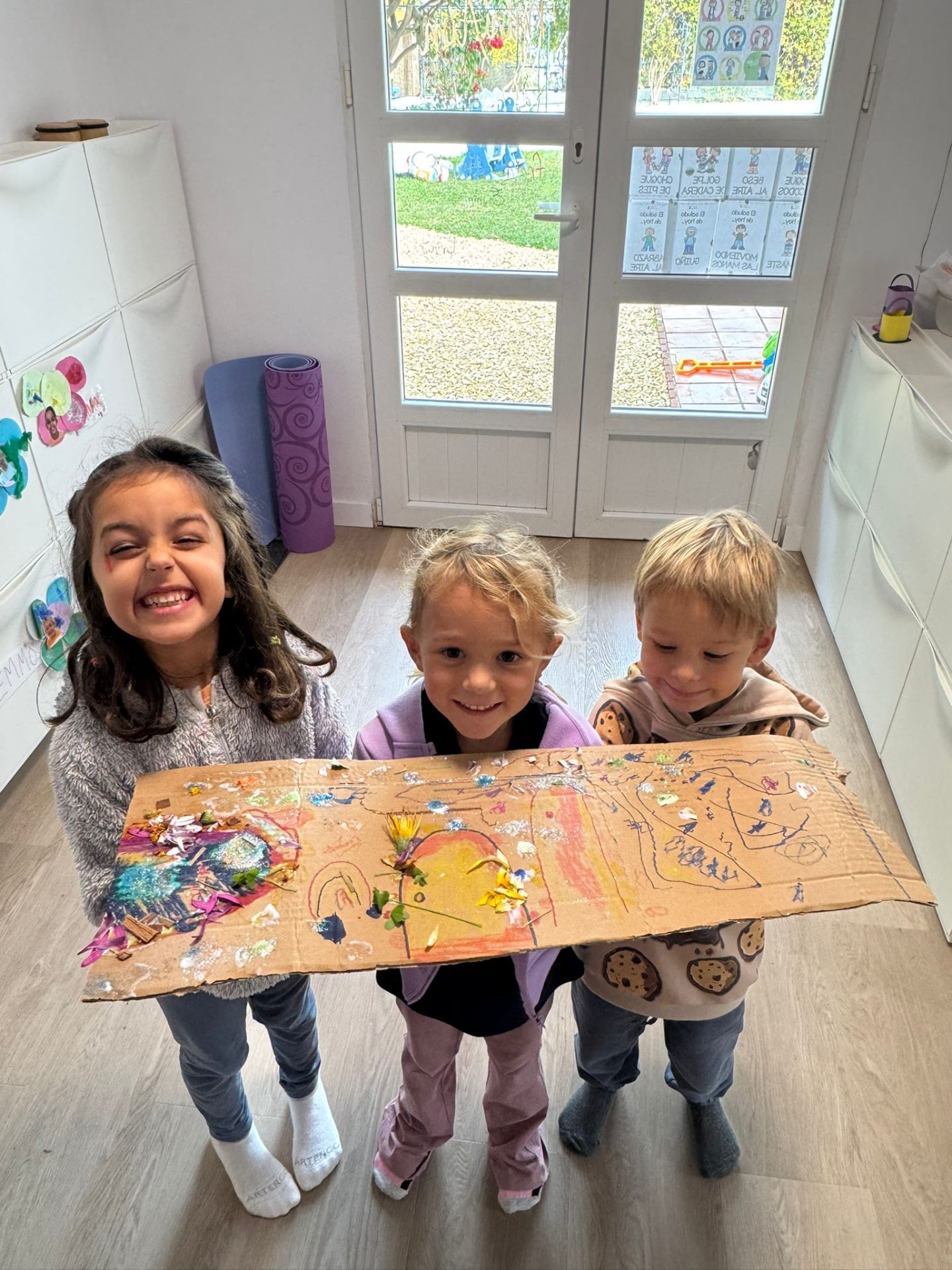 Tre børn viser stolt deres kunstprojekt